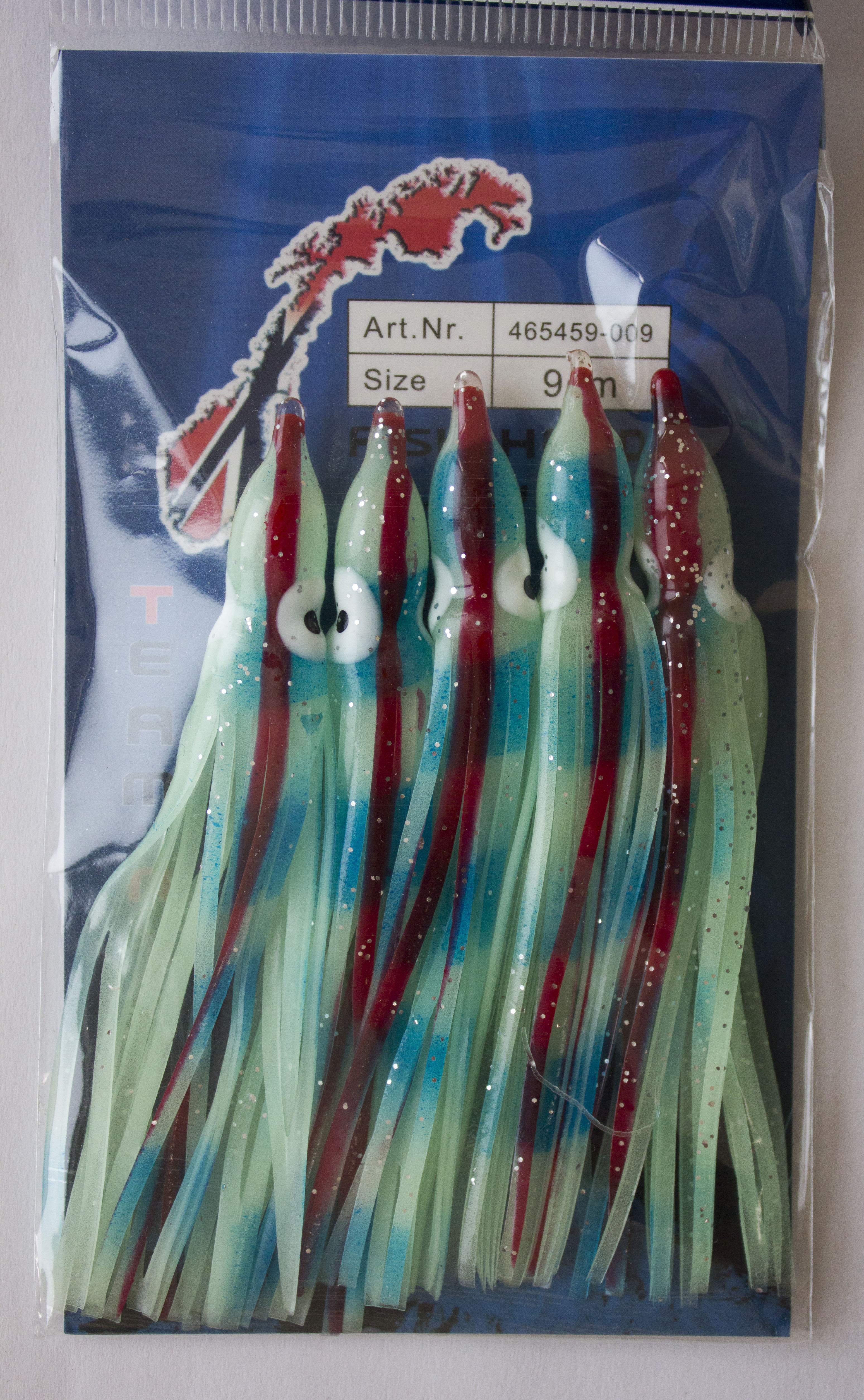 Nahaufnahme von Tintenfischködern in einer Verpackung, ideal zum Salzwasserangeln. Angelzubehör mit blauen, roten und grünen Akzenten. – Fishing Adventure GmbH